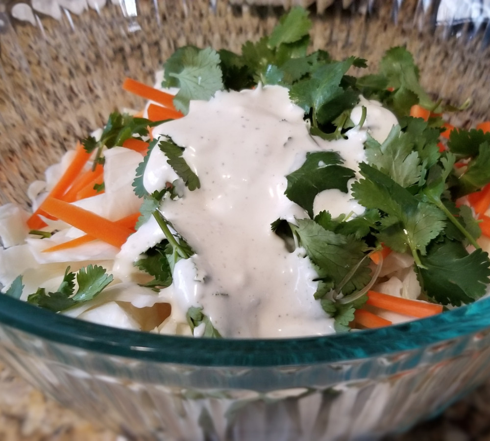 Cilantro, carrot, and cabbage with cilantro lime slaw dressing not yet fully mixed in.
