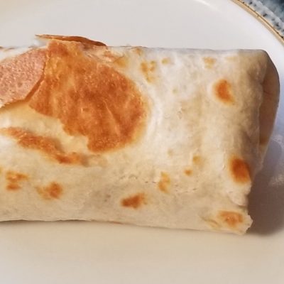 A close up of a browned bacon, egg, and mushroom breakfast burrito