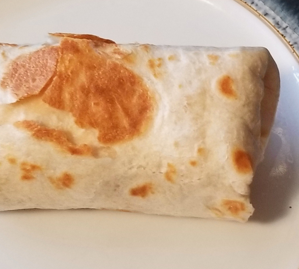 Close up of an egg, bacon, and mushroom breakfast burrito.