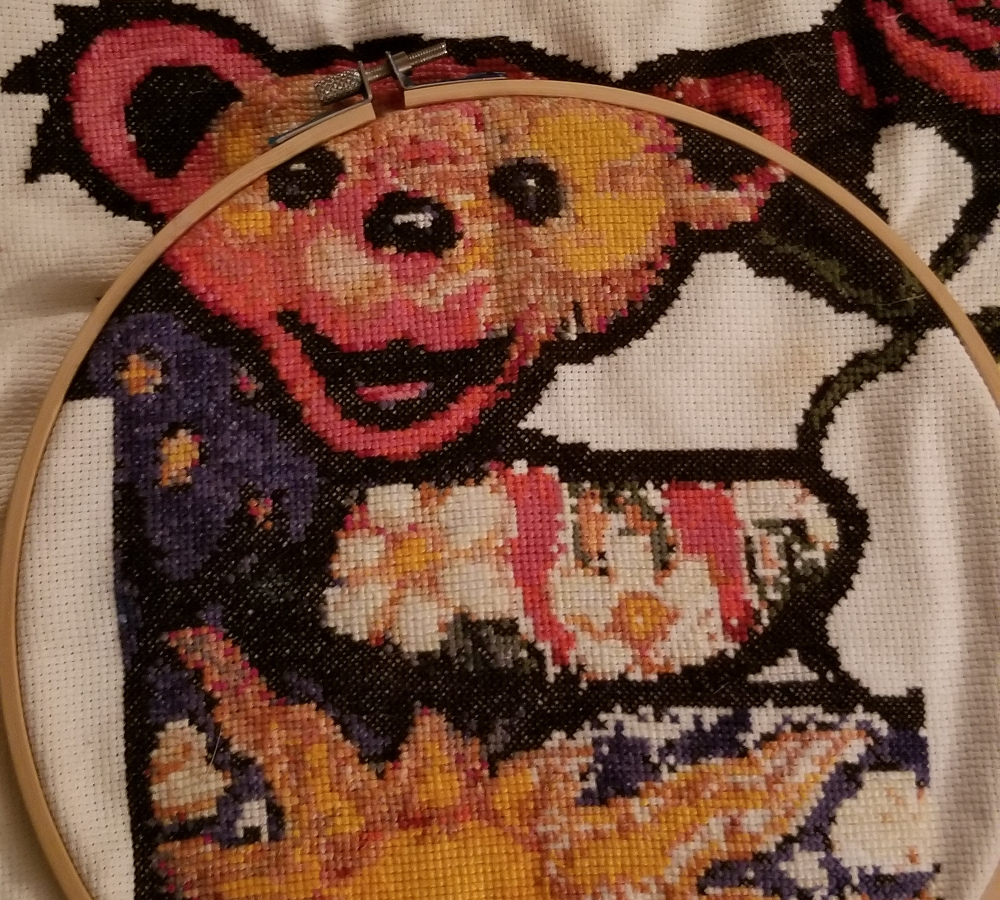 A cross stitch of a dancing bear