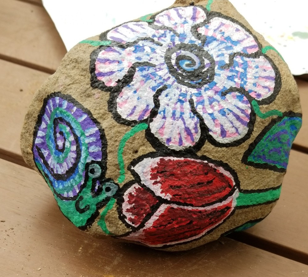 a painted rock with flowers and a snail