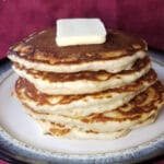 Stacked pancakes on a plate, topped with a pat of butter.