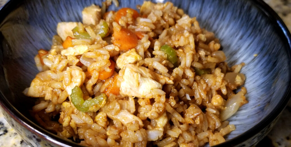 Fried rice in a bowl with chicken, celery, rice, egg, and carrots visible. 
