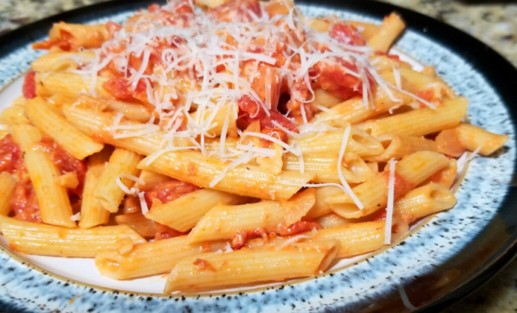A plate of creamy sun dried tomato pasta with parmesan sprinkled on top. 