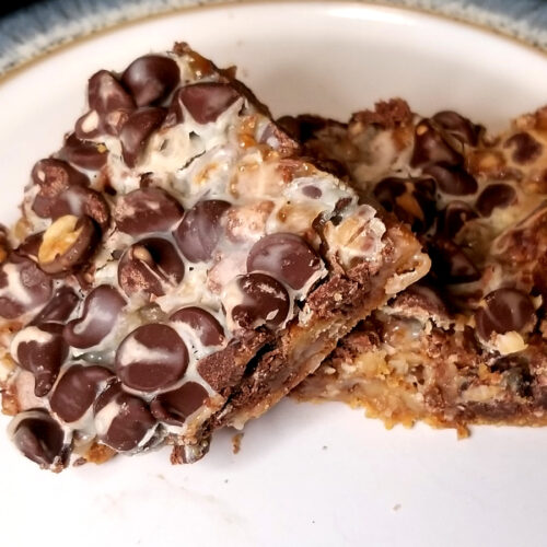 A zoomed in shot of one layer bar laying on top of another on a white plate with blue and gold edges.