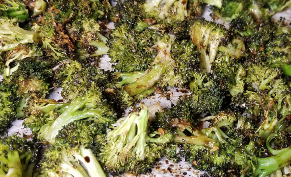 Roasted balsamic broccoli on a parchment paper covered cookie sheet.