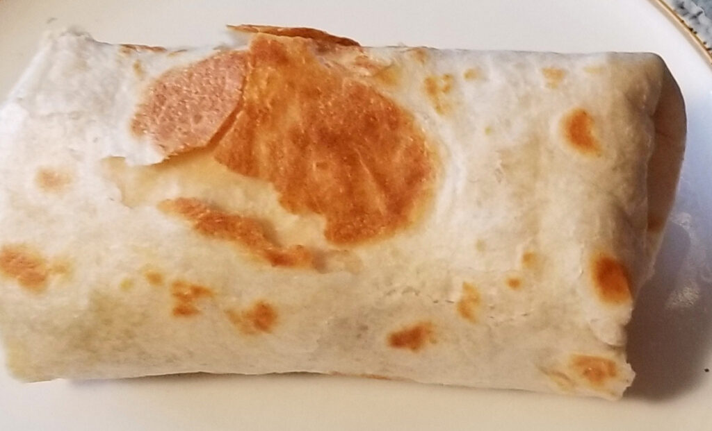 Close up of an egg, bacon, and mushroom breakfast burrito.