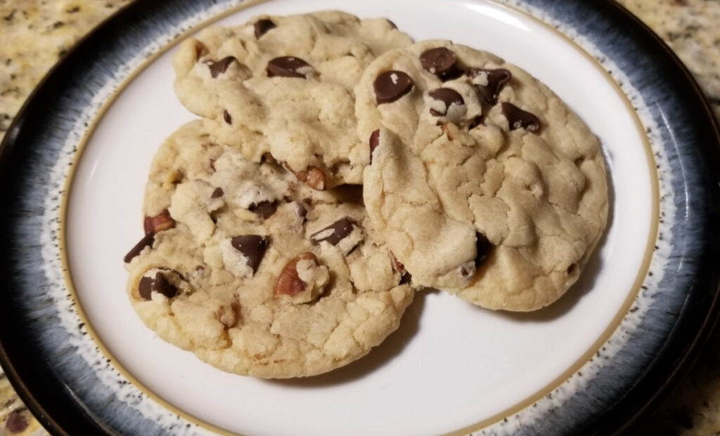 Three chocolate chip and pecan cookies stacked on each other