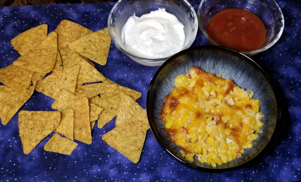 Cheesy corn dip with sour cream, salsa, and chips