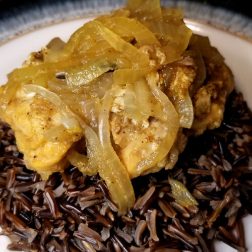 A close up of honey curry chicken on a pile of cooked wild rice.