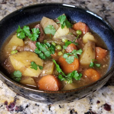Beef stew with carrots and potatoes, garnished with parsley.