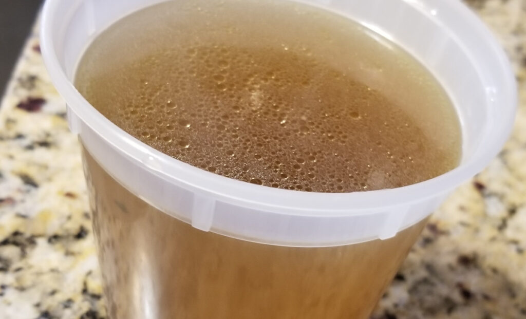 Chicken stock in a plastic freezer container. 
