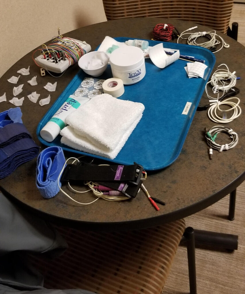 A table of wires, straps, and tape for my sleep study