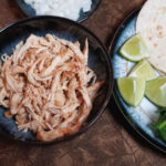 A close up of instant pot shredded chicken with taco accessories.