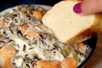 Minnesota wild rice soup being dipped into by French bread.