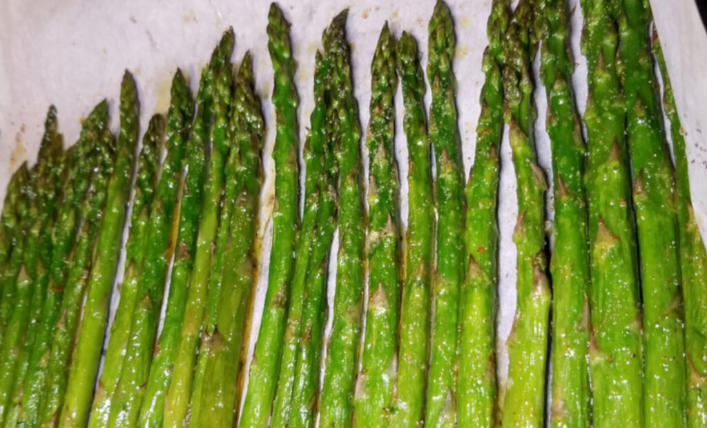 A close up of roasted asparagus on parchment paper.