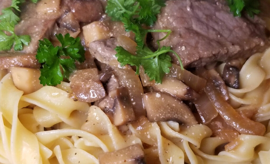 A zoomed in view of beef stroganoff sauce on pasta.