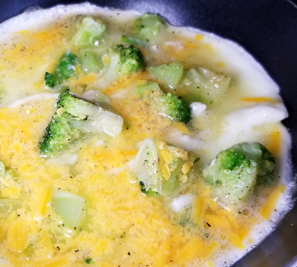 A close up of the egg white omelet in a pan, partway cooked.