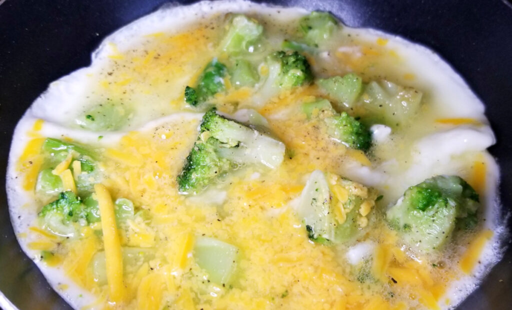A close up of the egg white omelet in a pan, partway cooked.