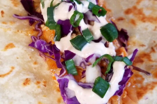 A close up of a not yet folded buffalo chicken wrap.