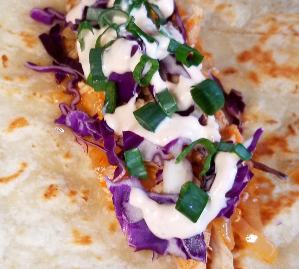 A close up of a not yet folded buffalo chicken wrap.