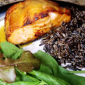 Close up of honey Dijon salmon plated with wild rice and a mixed lettuce salad.