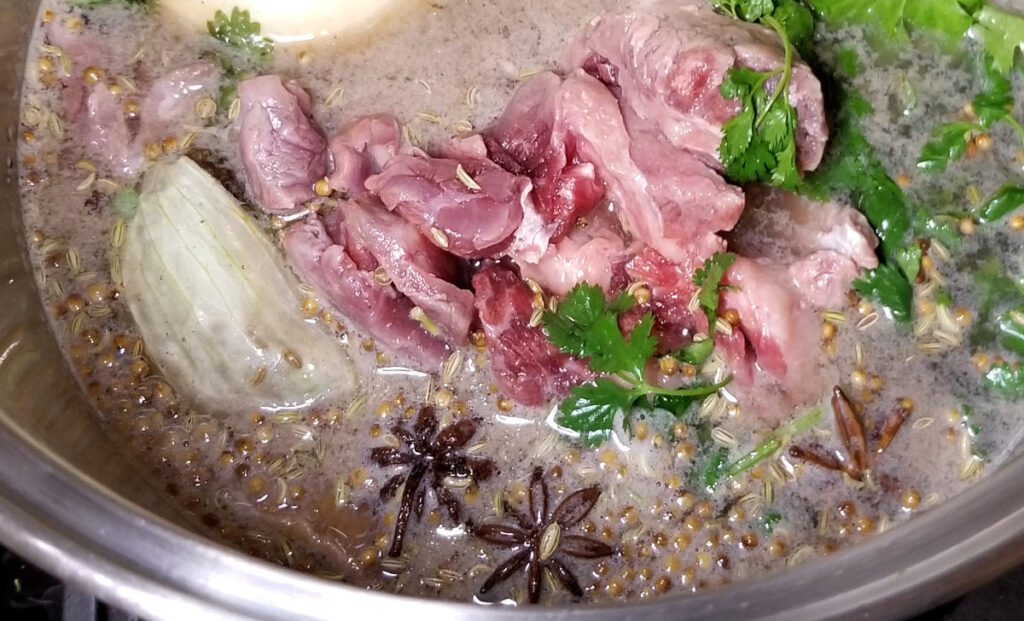 Beef pho broth simmering in a pot.