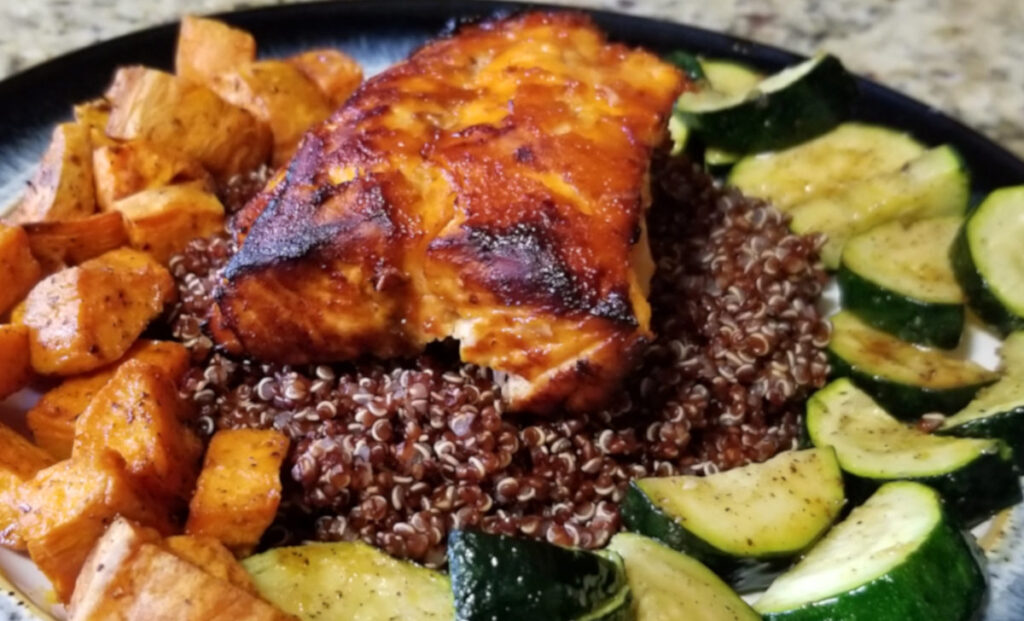Buffalo bourbon air fried salmon over red quinoa and plated with roasted sweet potatoes and zucchini.