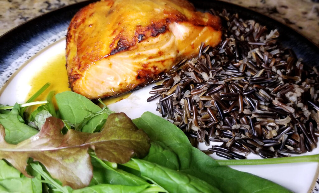 Honey Dijon salmon plated with wild rice and a mixed lettuce salad.