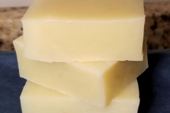 Homemade soap stacked three tall on a blue cloth.