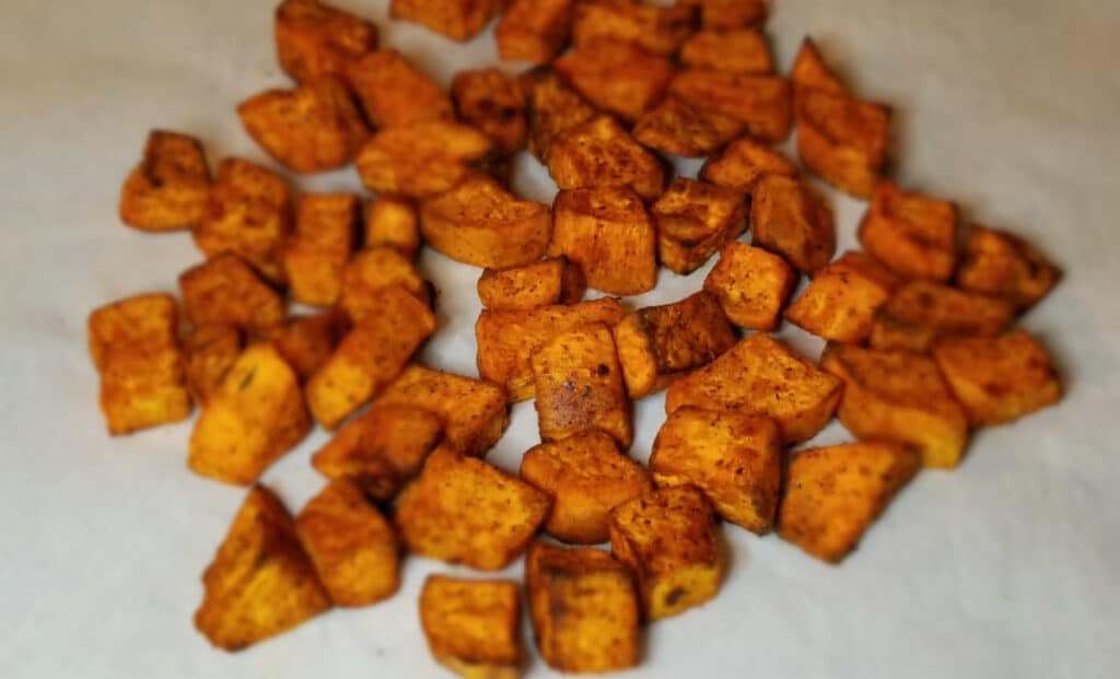 crispy seasoned sweet potatoes on a baking sheet.