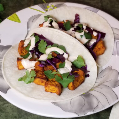 Two sweet potato tacos with cilantro, cabbage, and seasoned ranch