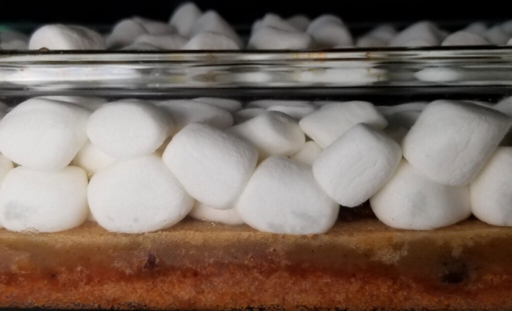 Bars layered with cooked crust and cookie layer and uncooked marshmallows. 