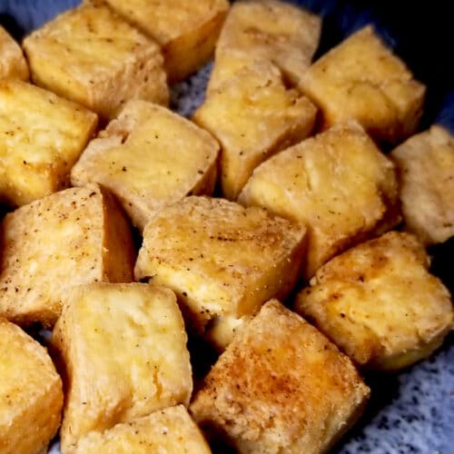 A close up of air fryer tofu on a blue plate.