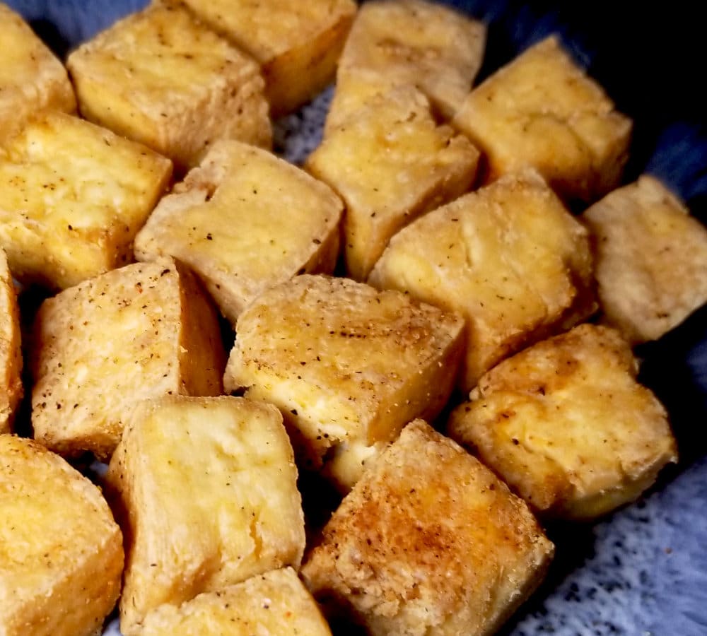 A close up of air fryer tofu on a blue plate.