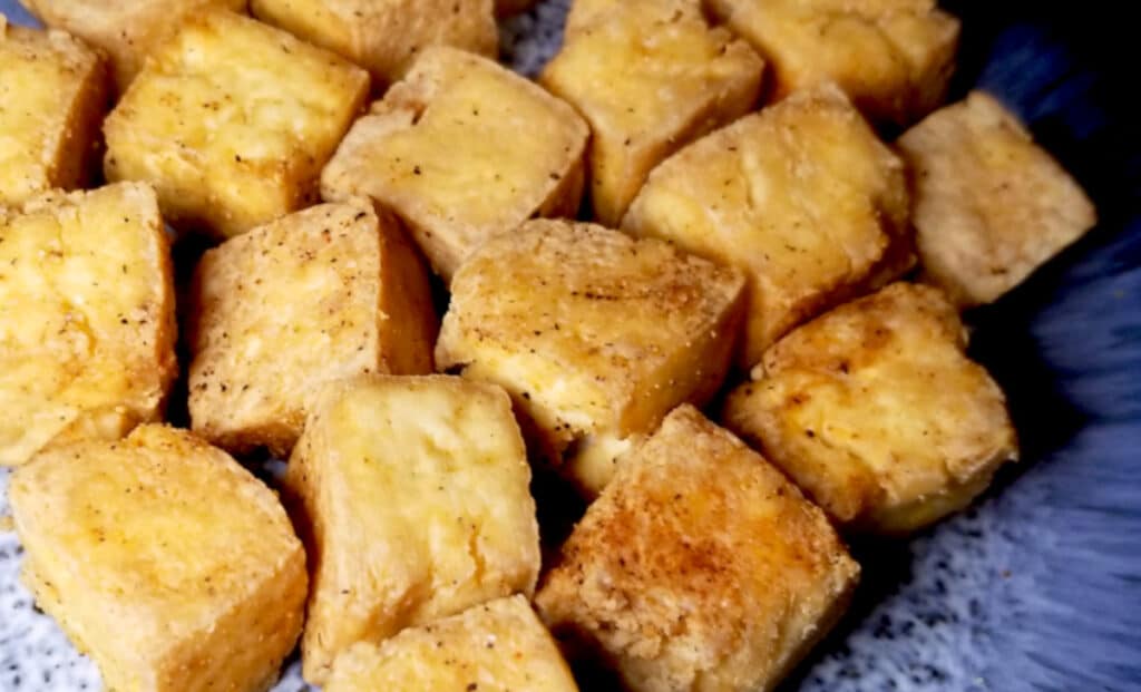 Crispy cubed tofu on a blue plate. 