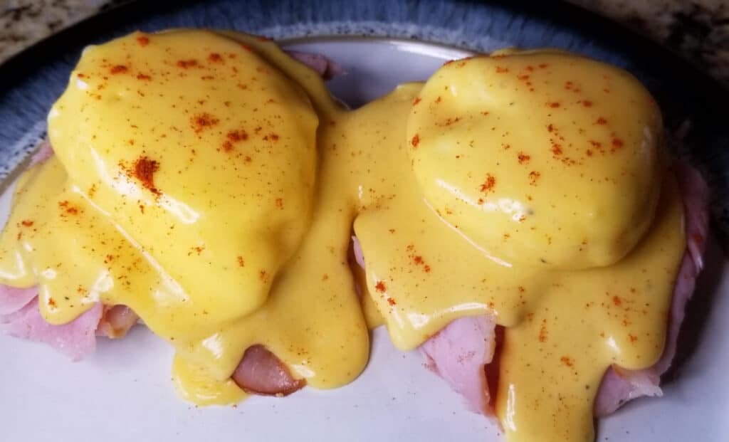 Eggs benedict on a plate, sprinkled with paprika. 