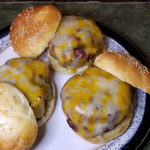 Three open faced juicy hamburgers with cheese and homemade buns.