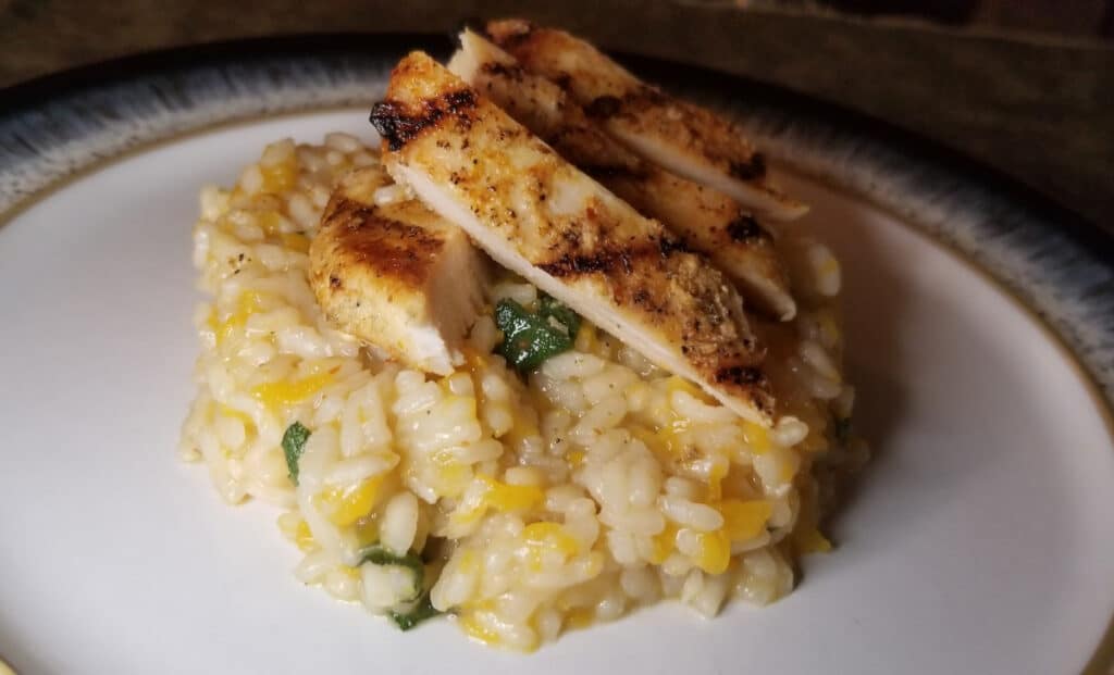 butternut squash risotto on a plate, topped with grilled chicken