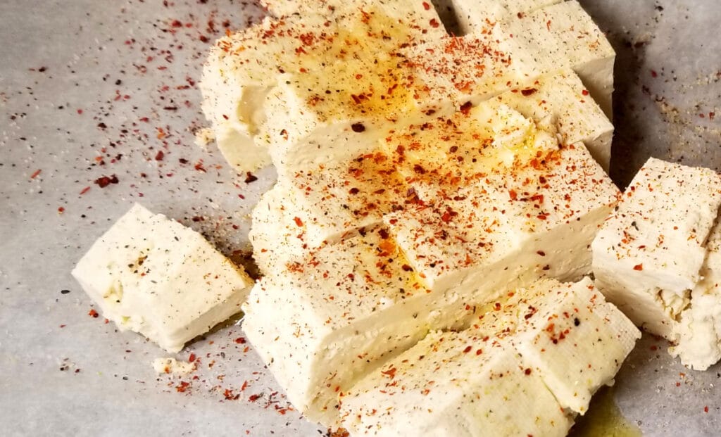 Uncooked cubed tofu drizzled with olive oil and seasoned. 
