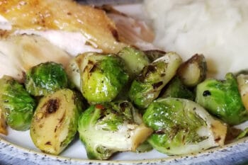 stovetop brussels sprouts on a plate with roasted chicken and mashed potatoes
