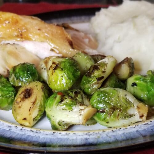 stovetop brussels sprouts on a plate with roasted chicken and mashed potatoes