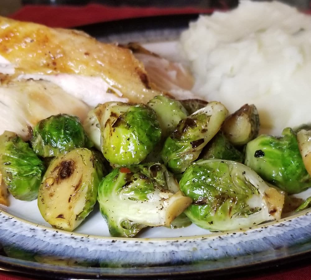 stovetop brussels sprouts on a plate with roasted chicken and mashed potatoes