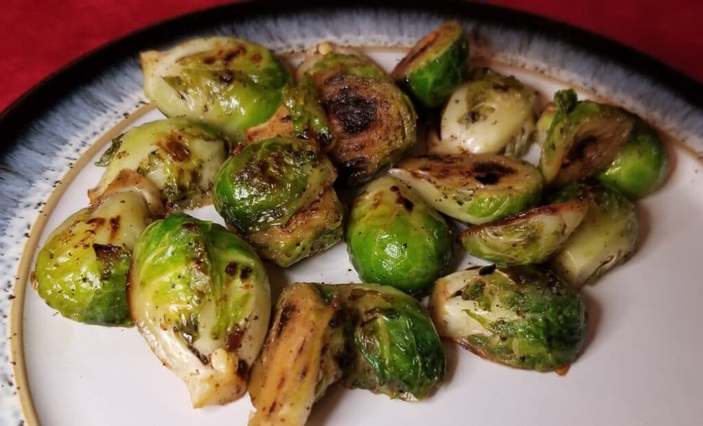 Browned sprouts on a blue and white plate and a red background. 