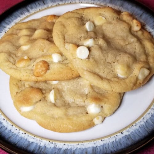 macadamia white chocolate cookies overlapped on a blue and white plate.
