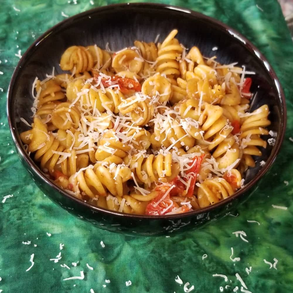 A bowl of cherry tomato pasta topped with parmesan.