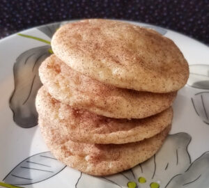 Snickerdoodles stacked on a floral plate.