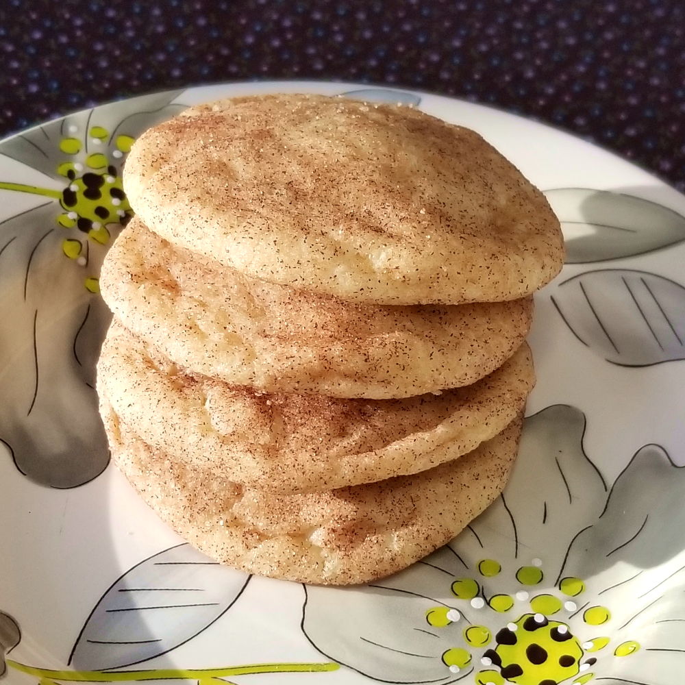 cinnamon sugar coated snickerdoodles stacked on a floral plate