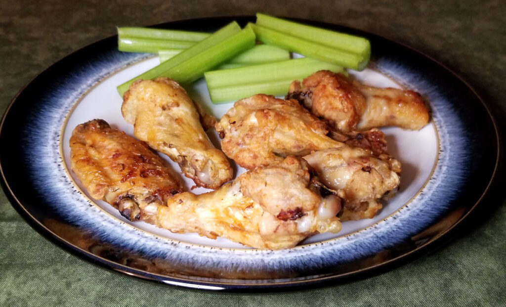 Air fryer wings on a plate with celery.
