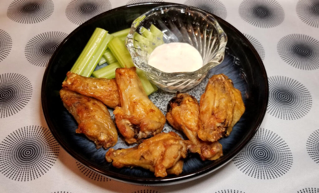 Crispy wings on a plate with celery and ranch. 